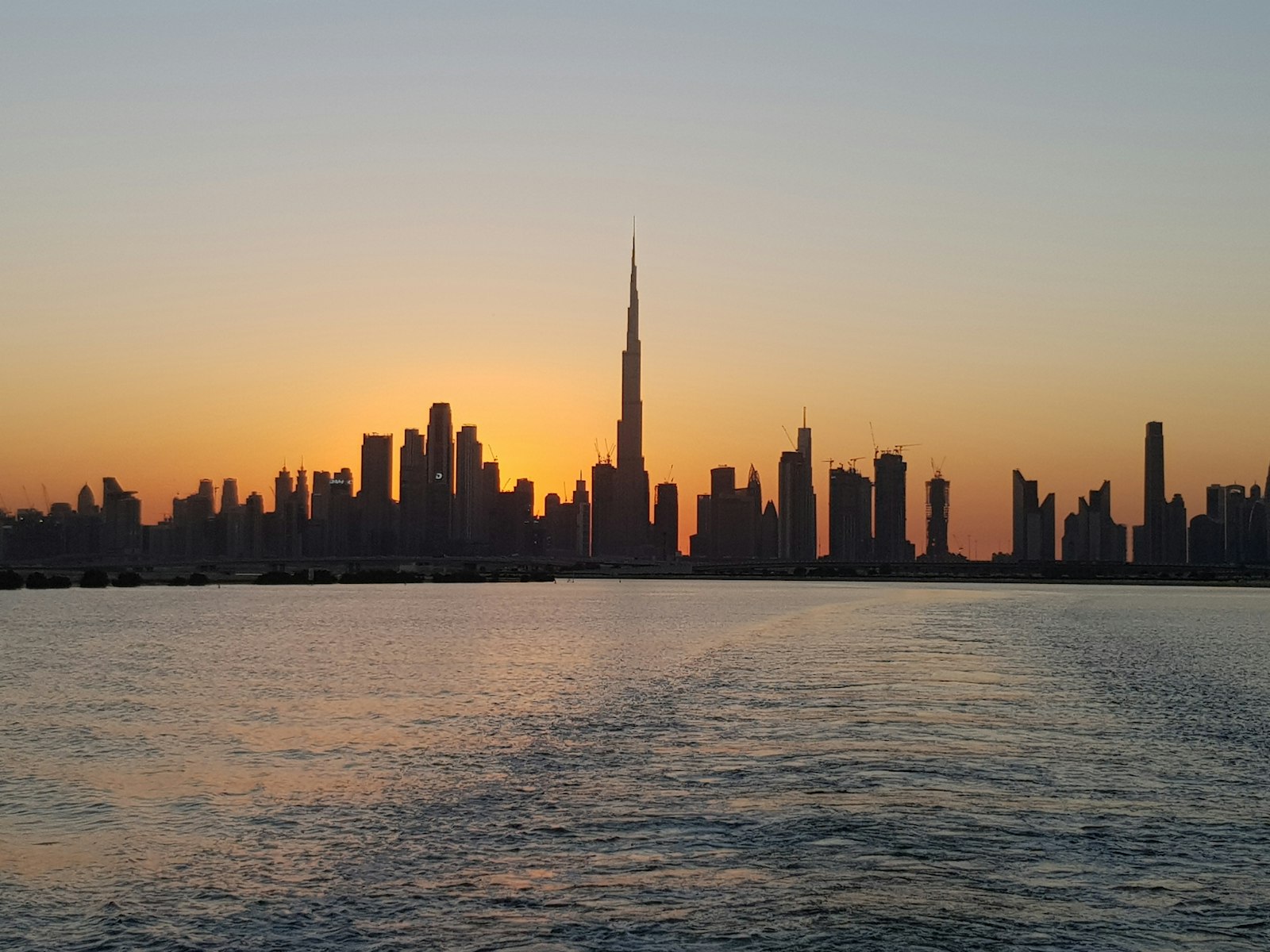 Dubai skyline glowing at sunset across the water